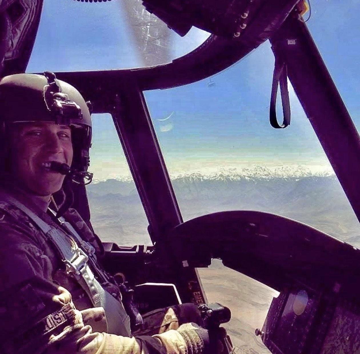 In a helicopter cockpit, with mountains visible through the windshield.